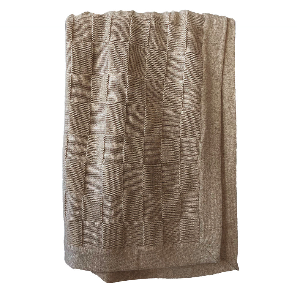 A light brown throw blanket with a classic checkers pattern, draped and displaying the texture of the knit.